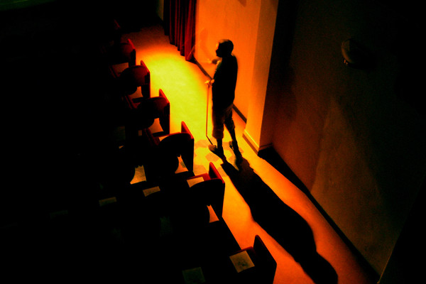 An actor walks alone in an empty theatre.